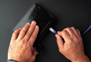 Man's hand plugging internet cable into wifi router