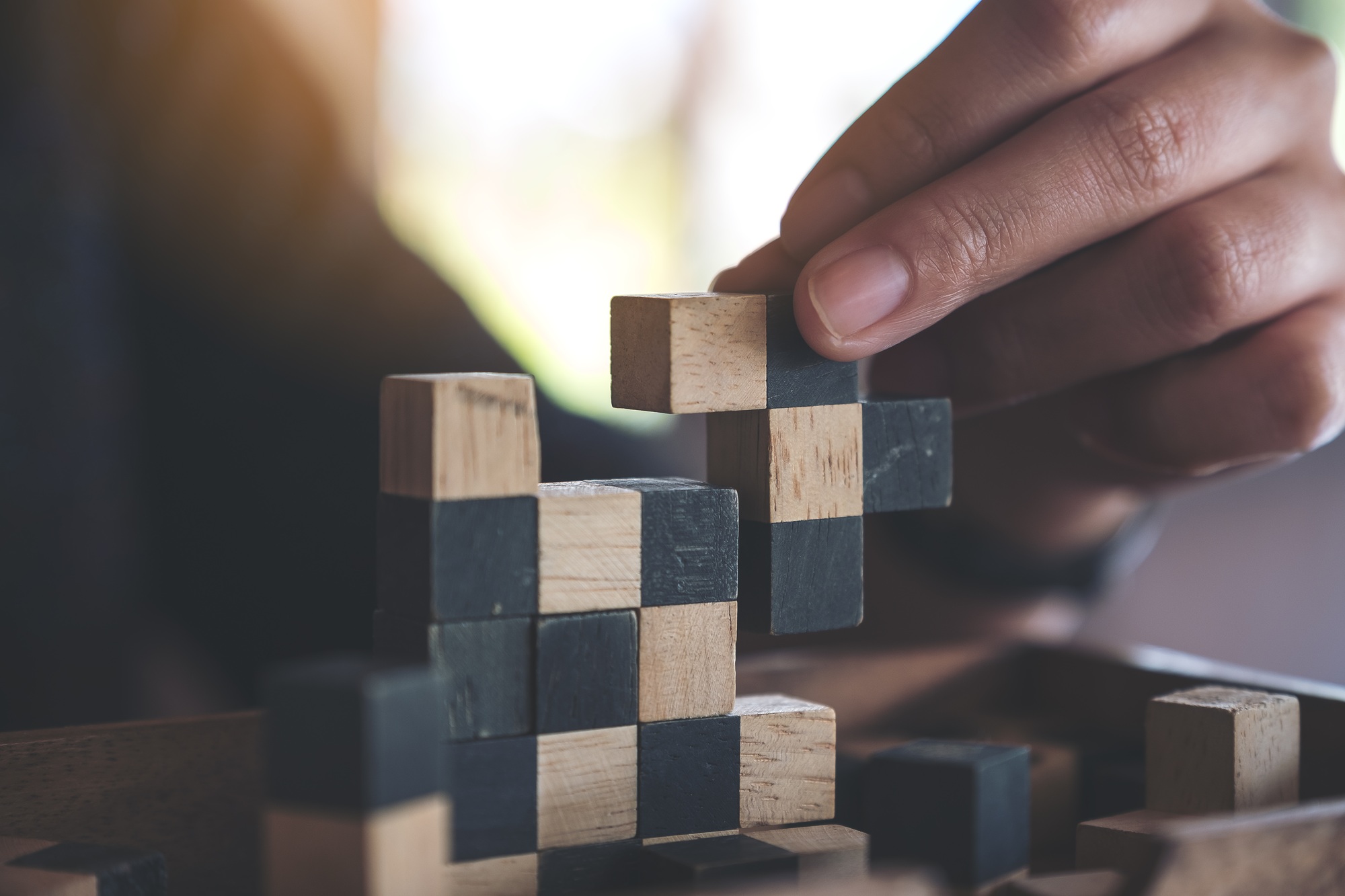 Closeup image of people playing and building wooden puzzle game