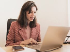 Concentrated young lady using laptop and sitting at table