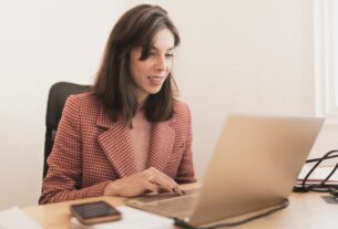 Concentrated young lady using laptop and sitting at table